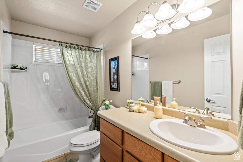 Full bath with shower / bath combo, vanity, a chandelier, and tile patterned floors