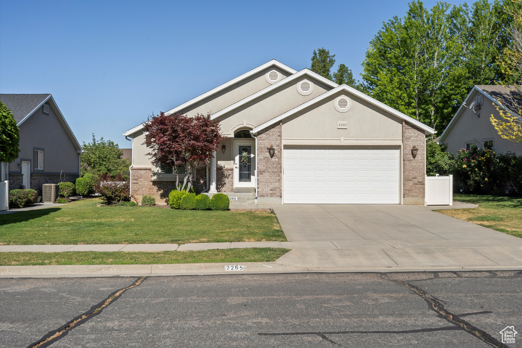 View of front of property featuring a garage, a front lawn, driveway, and brick siding