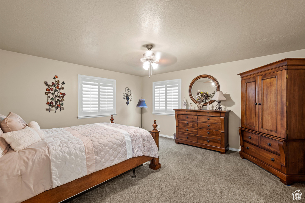 Bedroom featuring light colored carpet, a ceiling fan, and a textured ceiling