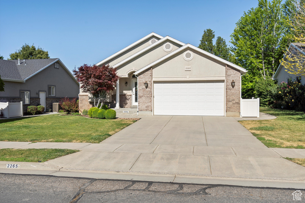 View of front facade with an attached garage, a front lawn, driveway, and brick siding