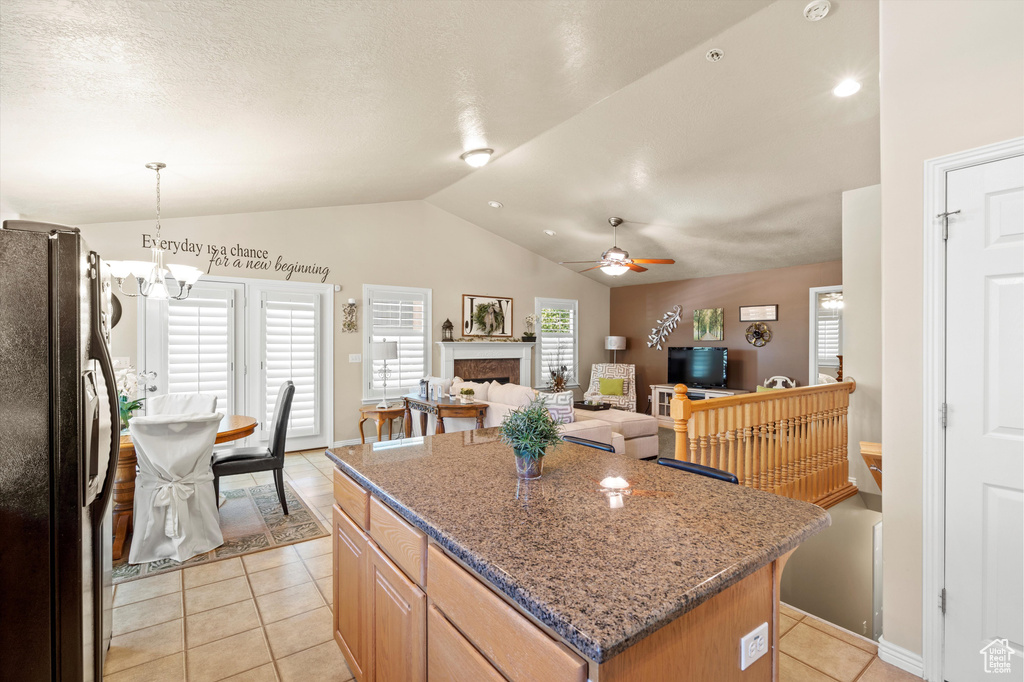 Kitchen with freestanding refrigerator, ceiling fan, light tile patterned floors, lofted ceiling, and a kitchen island