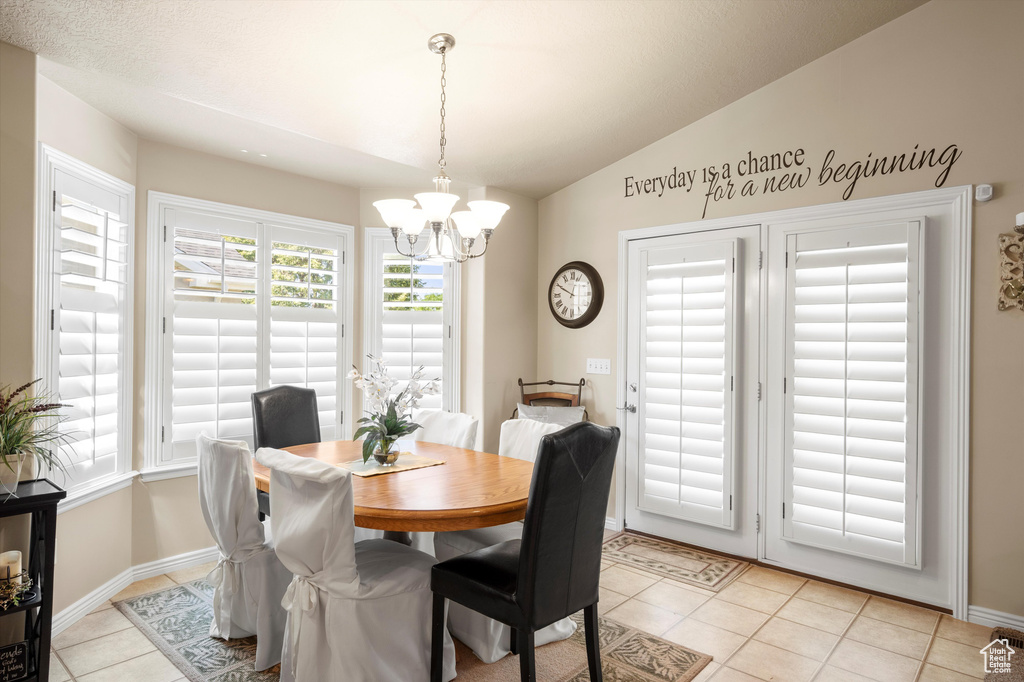 Dining room with a chandelier, light tile patterned floors, and lofted ceiling