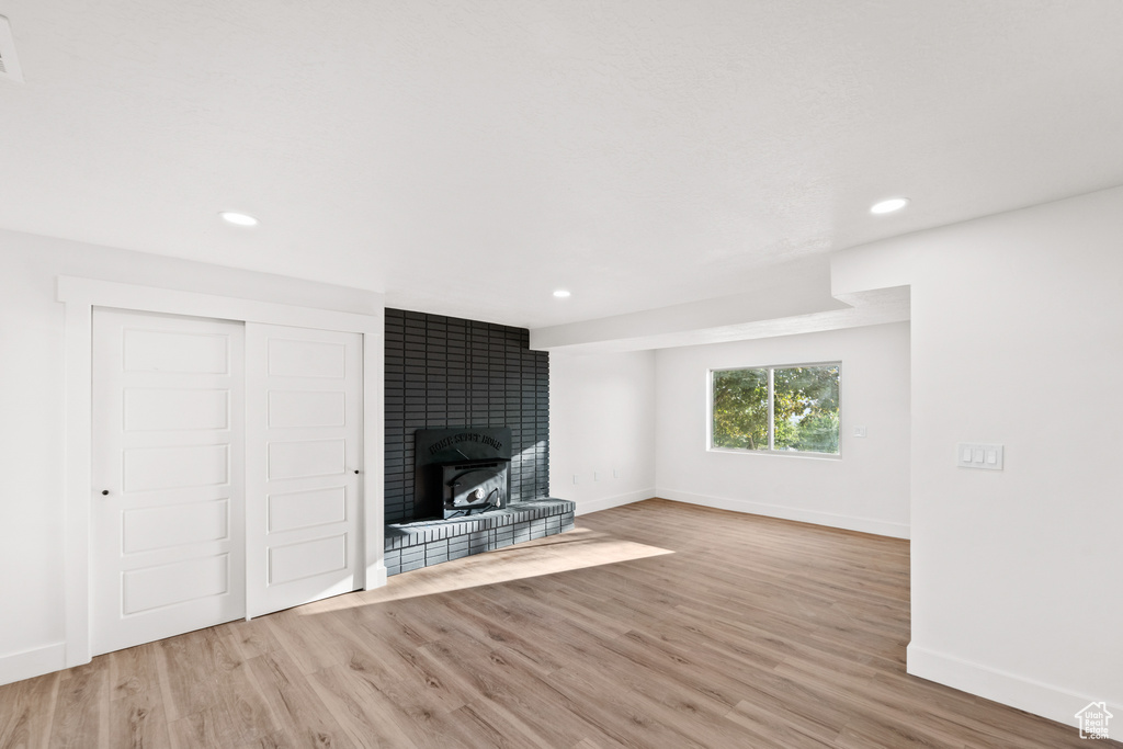 Unfurnished living room featuring wood finished floors, recessed lighting, and a brick fireplace