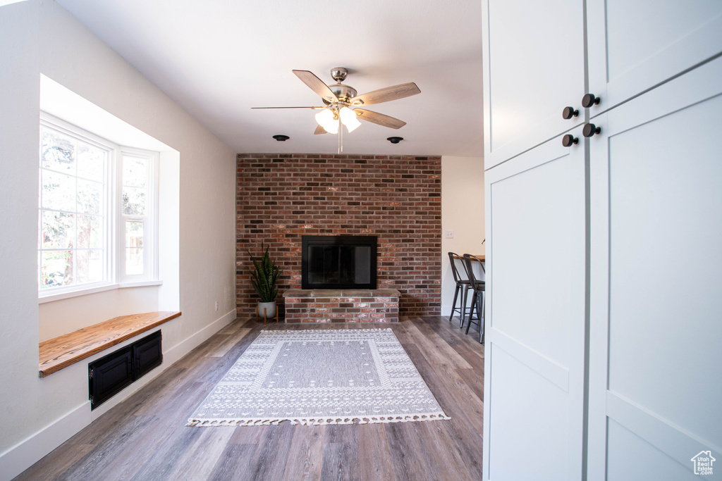 Unfurnished living room featuring ceiling fan, wood finished floors, and a fireplace