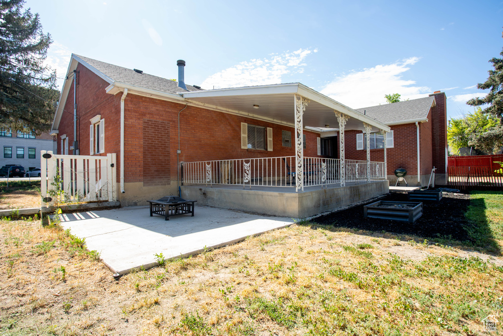 Back of property featuring brick siding, a patio, a yard, and an outdoor fire pit