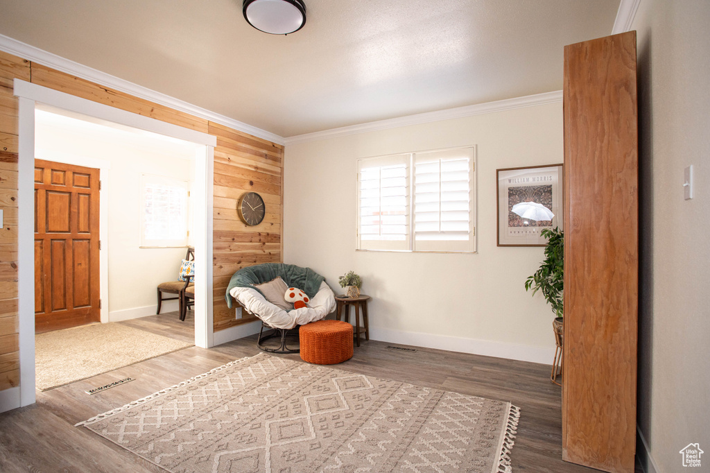 Living area featuring wood walls, crown molding, and wood finished floors