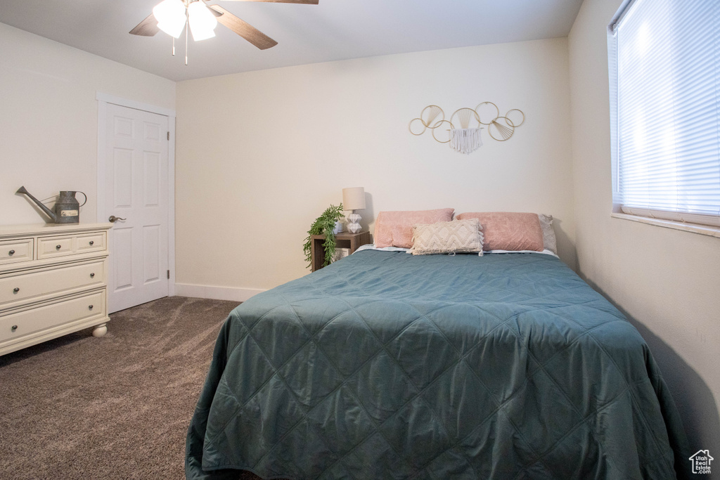 Bedroom with dark carpet and a ceiling fan