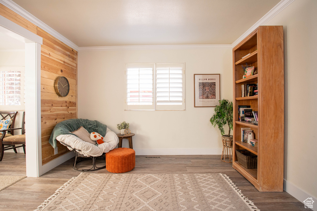 Living area with crown molding, wood finished floors, and wood walls