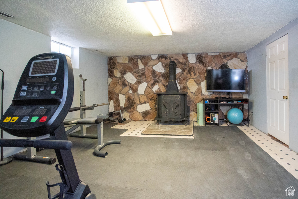 Workout room with a textured ceiling and a wood stove