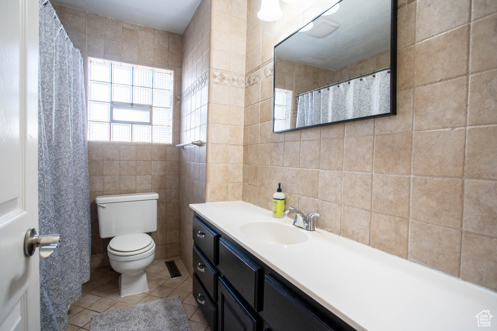 Full bathroom featuring tile walls, vanity, and tile patterned floors