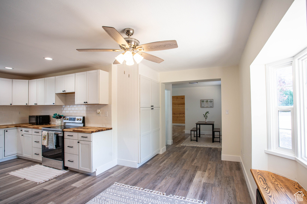 Kitchen with stainless steel range with electric cooktop, butcher block counters, white cabinets, decorative backsplash, and wood finished floors