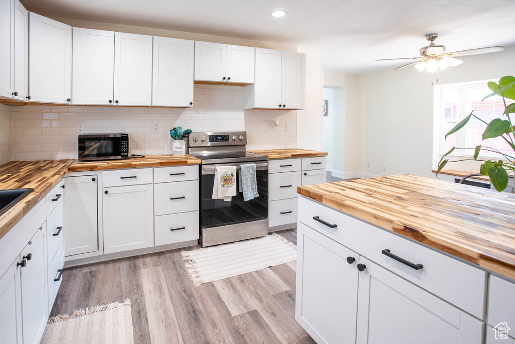 Kitchen featuring wood counters, stainless steel appliances, recessed lighting, decorative backsplash, and white cabinetry