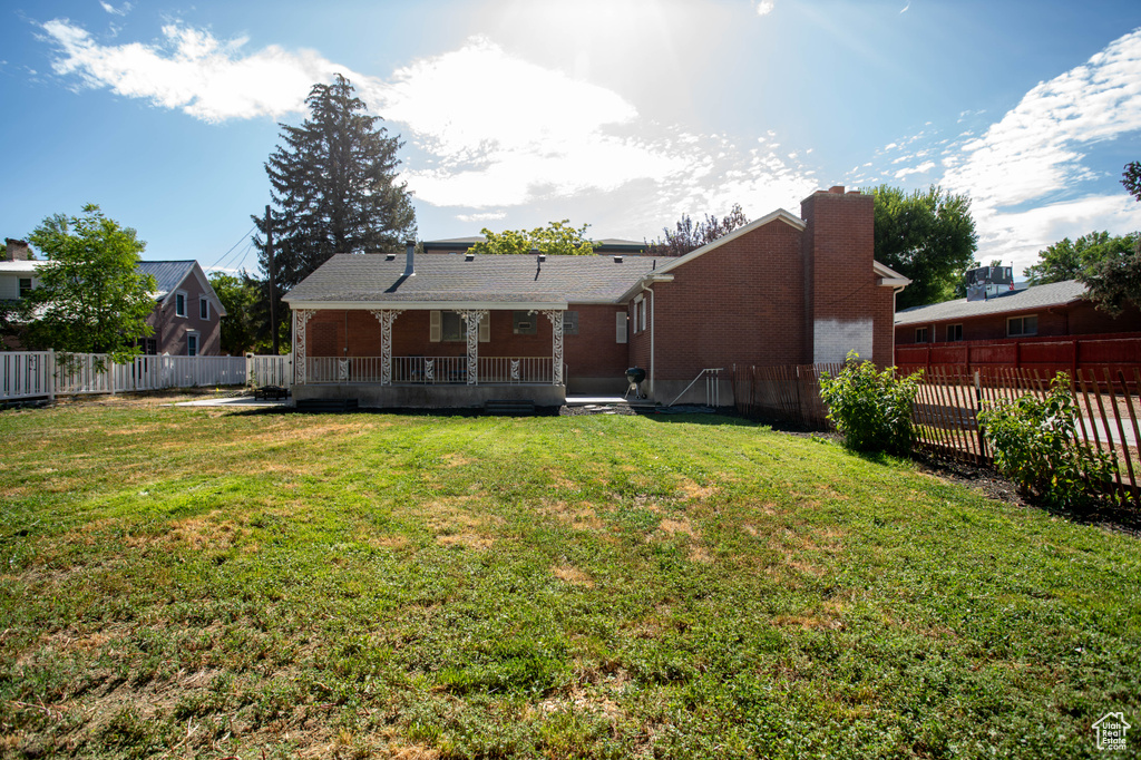 Rear view of house with a fenced backyard, a wooden deck, a chimney, and brick siding