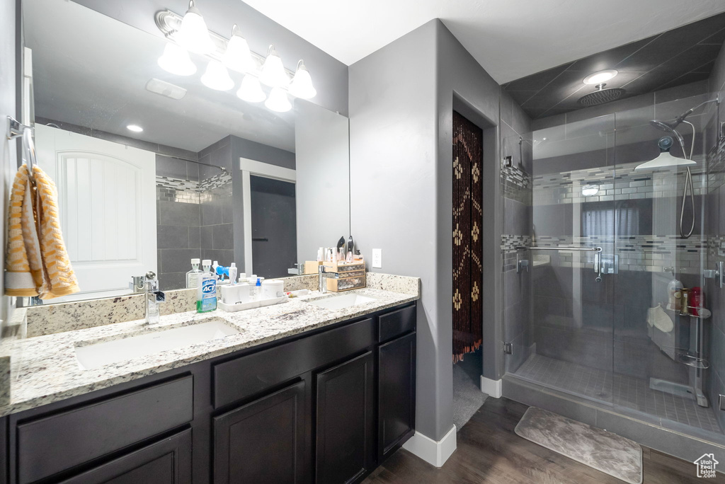 Bathroom with a stall shower, double vanity, and wood finished floors