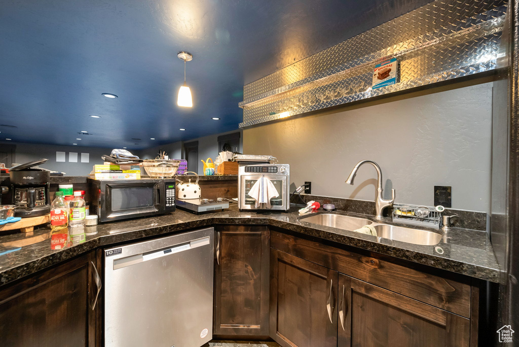 Kitchen featuring dishwasher, black microwave, dark stone countertops, and dark brown cabinetry