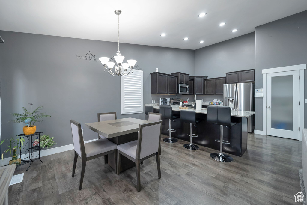 Dining space with wood finished floors, a chandelier, recessed lighting, and a towering ceiling