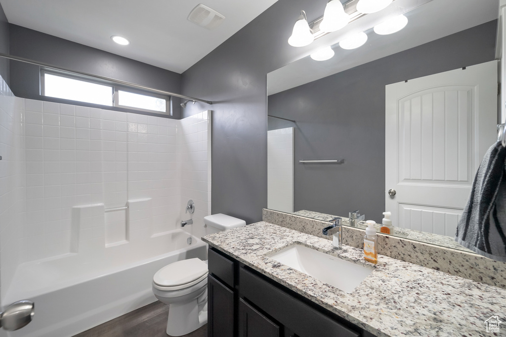 Bathroom with vanity, wood finished floors, and washtub / shower combination