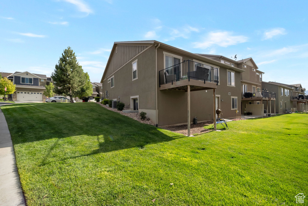 View of side of property with a residential view, a yard, stucco siding, and a balcony