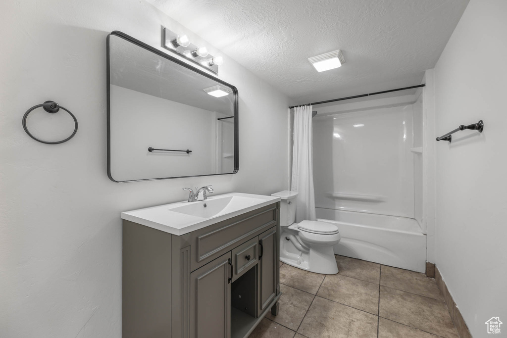 Full bathroom with vanity, shower / bath combination with curtain, tile patterned floors, and a textured ceiling