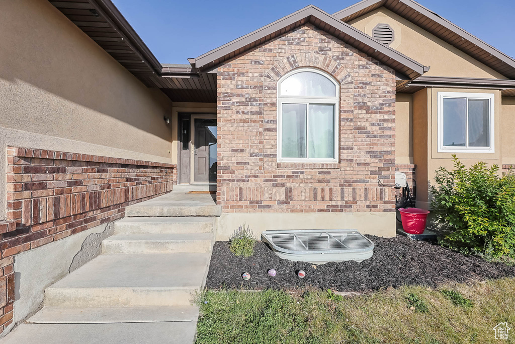 View of exterior entry with stucco siding and brick siding