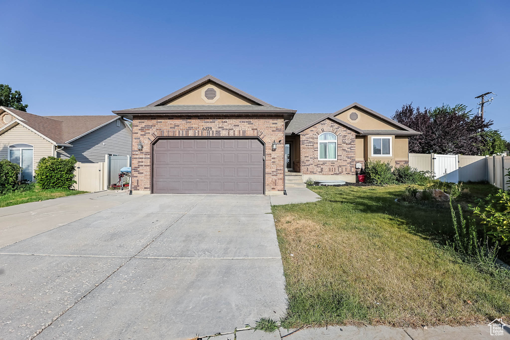 Ranch-style house with a garage, concrete driveway, brick siding, and a gate