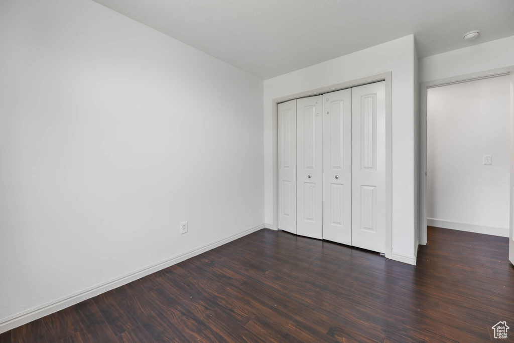 Unfurnished bedroom with dark wood-type flooring and a closet