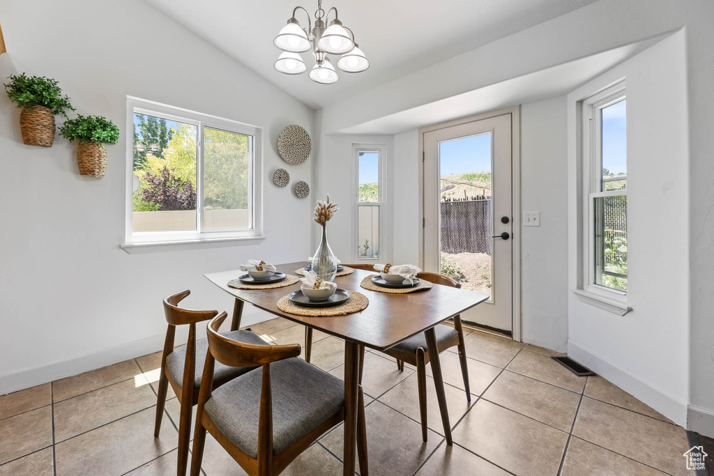 Dining area with light tile patterned flooring, vaulted ceiling, and a chandelier