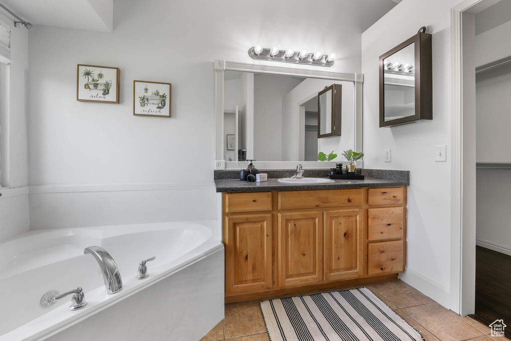 Bathroom featuring vanity, a garden tub, and tile patterned flooring