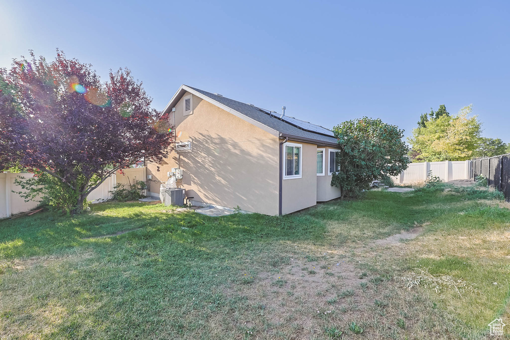 View of home's exterior featuring stucco siding, solar panels, and a fenced backyard