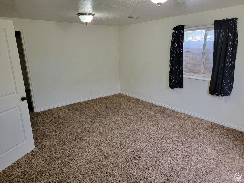 Carpeted spare room with baseboards and a textured ceiling