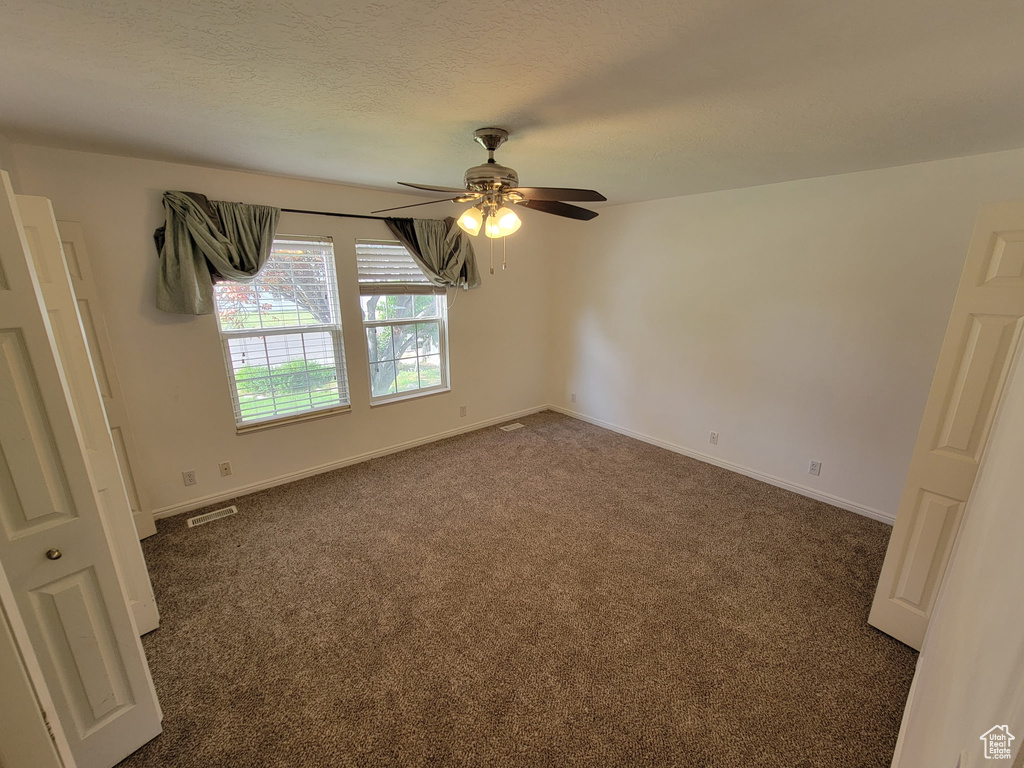 Unfurnished room featuring a ceiling fan and dark colored carpet