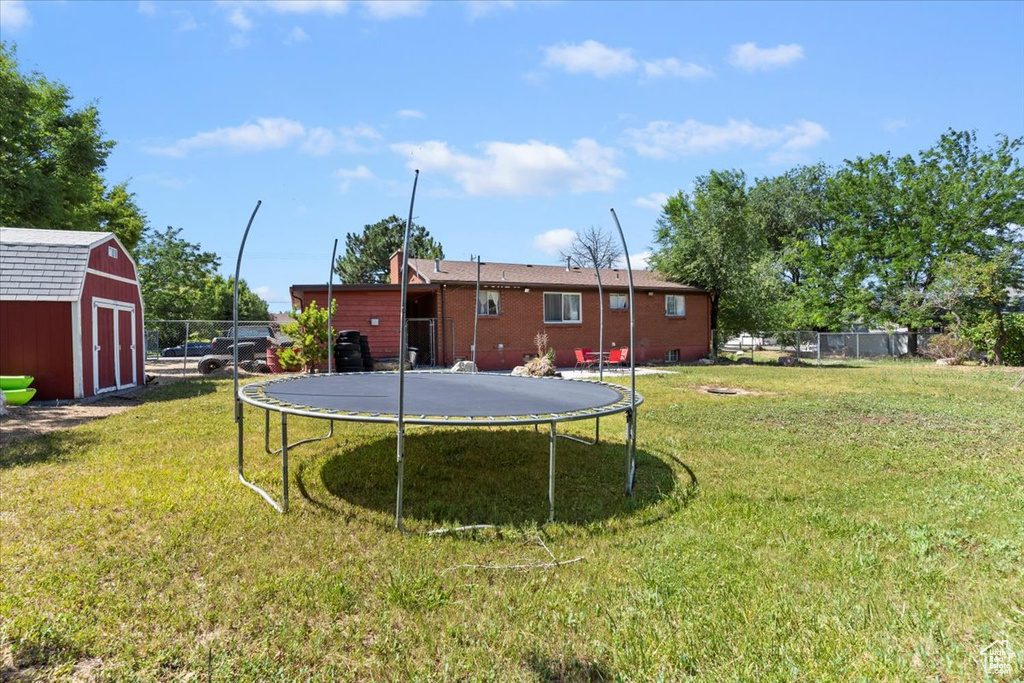 View of yard with a trampoline and a storage unit