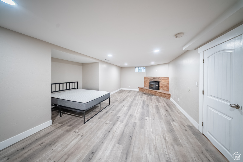 Bedroom with light wood-type flooring, a stone fireplace, and recessed lighting