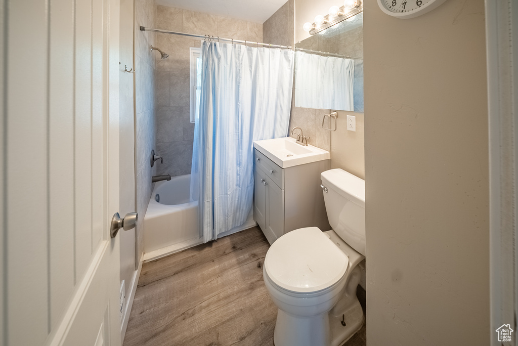 Full bathroom with wood finished floors, shower / bath combo with shower curtain, and vanity