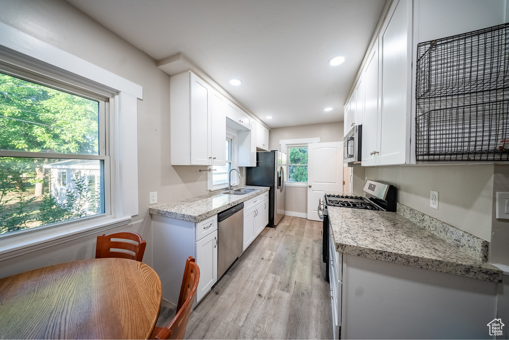 Kitchen featuring stainless steel appliances, light wood finished floors, white cabinetry, recessed lighting, and light stone counters