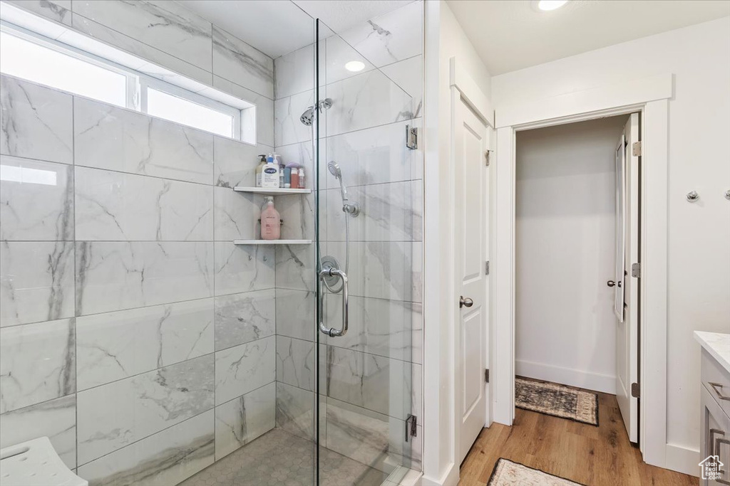 Full bath with a stall shower, vanity, and wood finished floors