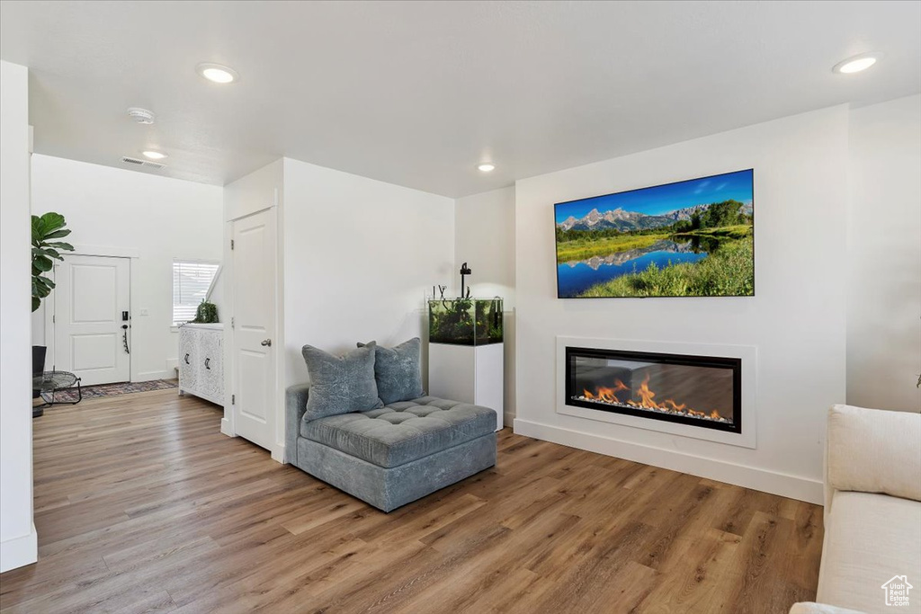 Sitting room with wood finished floors, a glass covered fireplace, and recessed lighting
