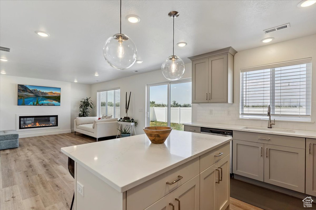 Kitchen with gray cabinets, recessed lighting, tasteful backsplash, light wood-style floors, and a kitchen island