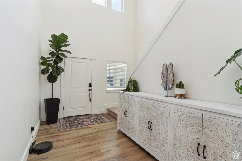 Foyer entrance featuring light wood-type flooring and a towering ceiling