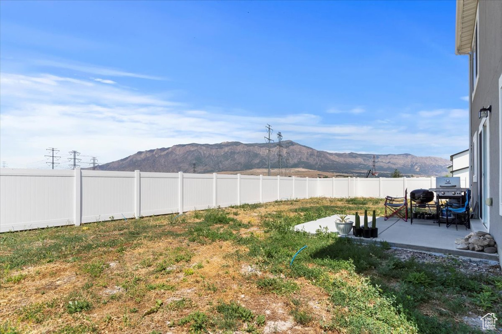 Fenced backyard featuring a mountain view and a patio area