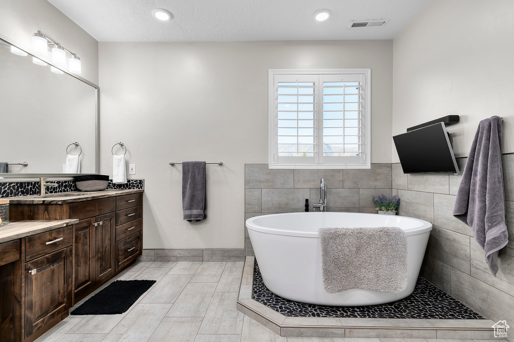 Bathroom with vanity, a soaking tub, and recessed lighting