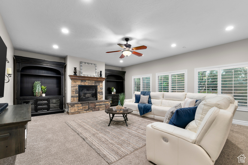 Carpeted living room featuring recessed lighting, ceiling fan, and a fireplace