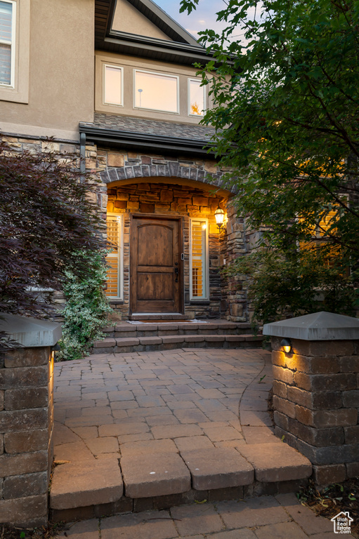 View of exterior entry with stucco siding and stone siding