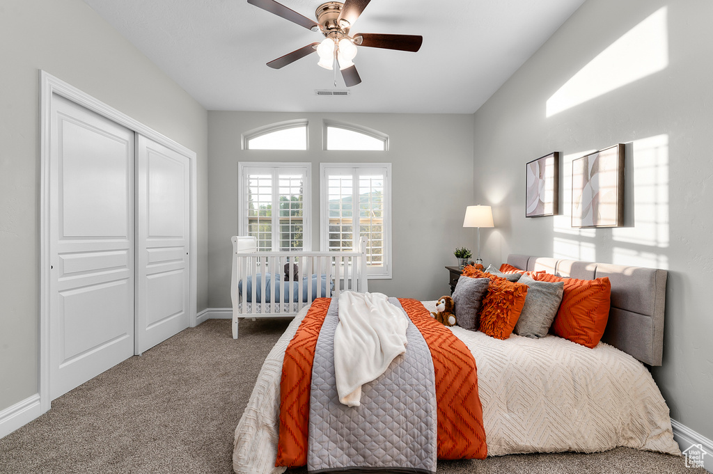 Carpeted bedroom featuring ceiling fan and a closet