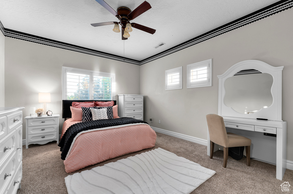 Bedroom with light carpet, multiple windows, a textured ceiling, a ceiling fan, and crown molding