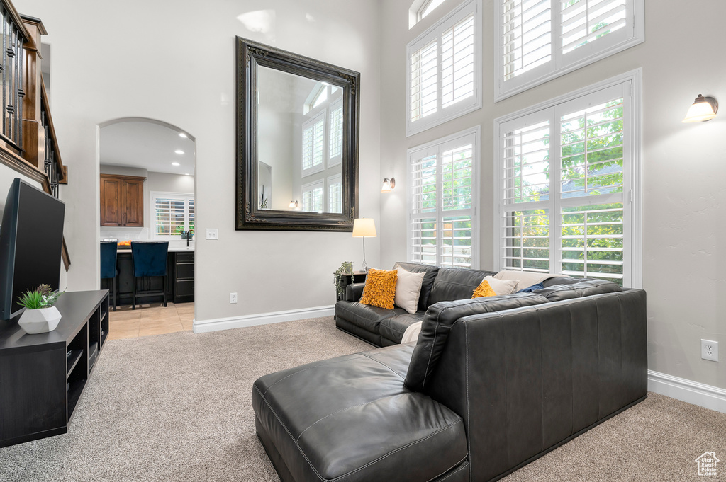 Living area featuring a towering ceiling, light carpet, and arched walkways