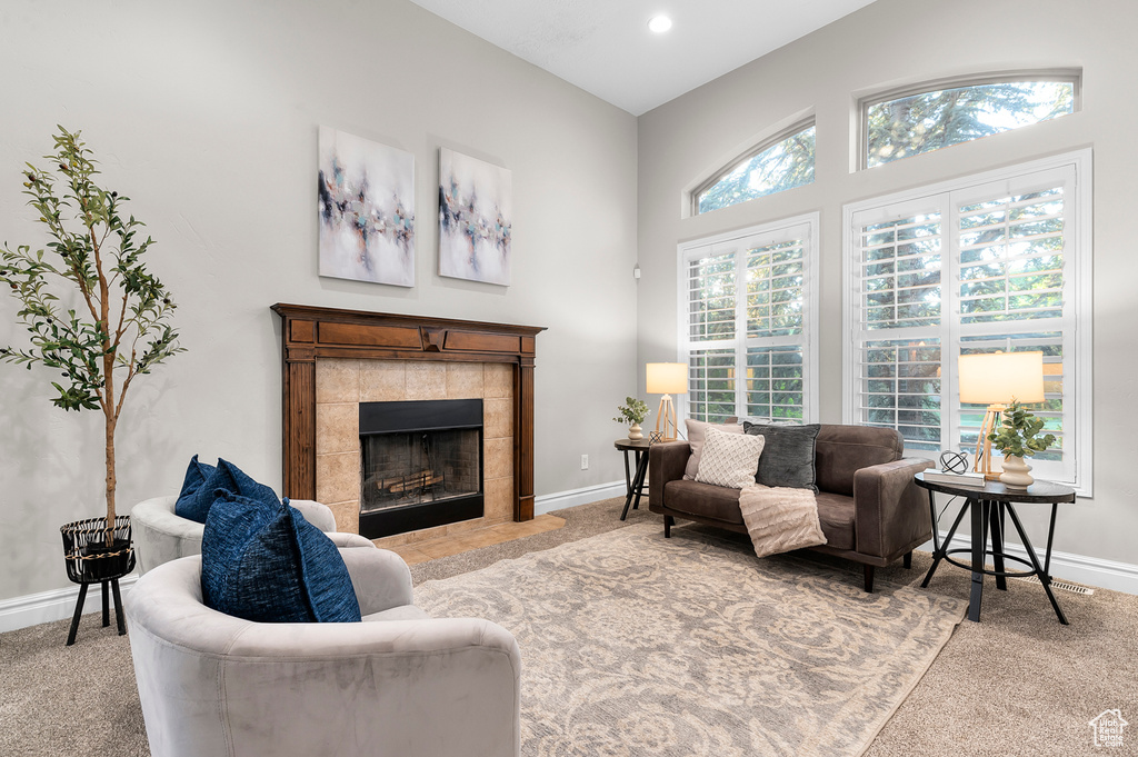 Living room with light carpet, a tile fireplace, recessed lighting, and a towering ceiling