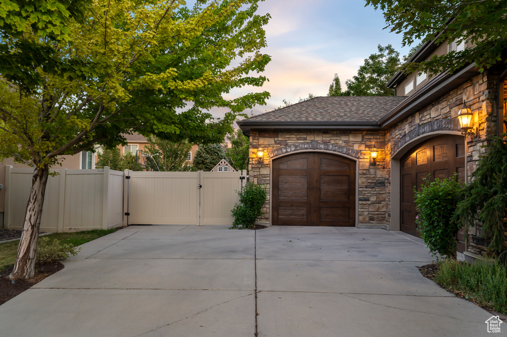 Garage at dusk featuring a gate and concrete driveway