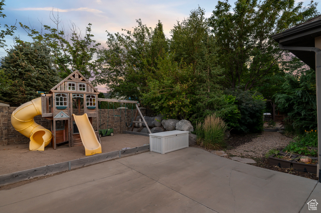 Playground at dusk featuring a playground and a patio area