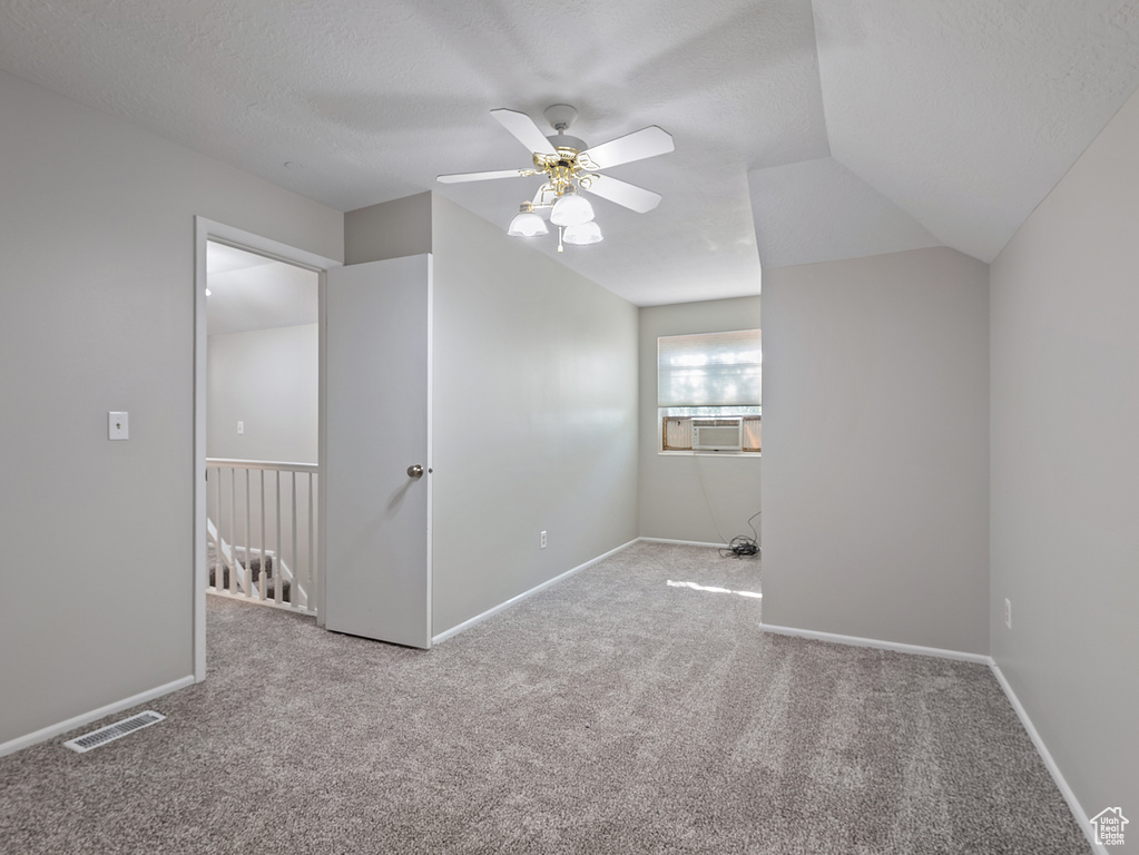 Carpeted spare room featuring a ceiling fan, a textured ceiling, and cooling unit
